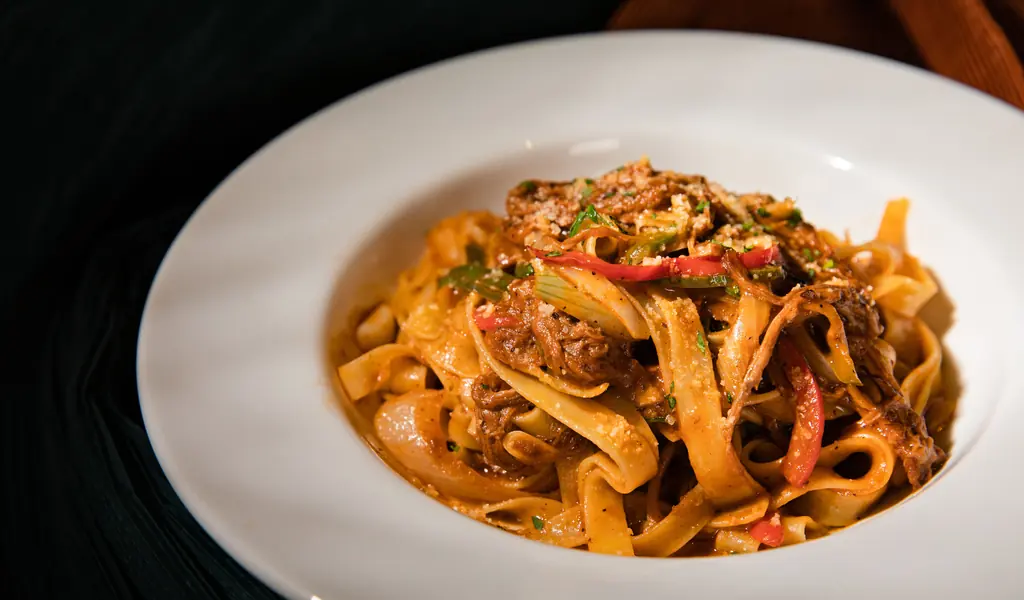 Tagliatelle med långkokt ragù på en vit tallrik.