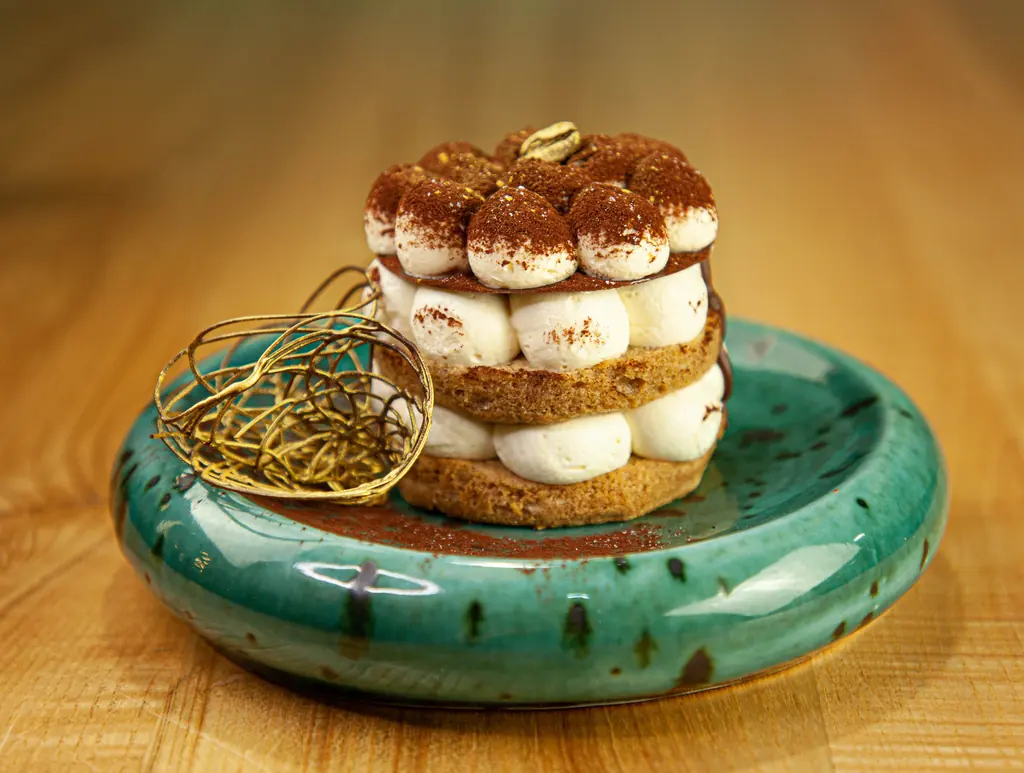 Tiramisu serverad på en grön keramiktallrik.