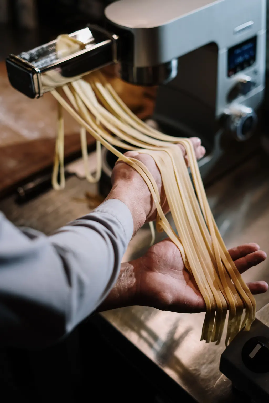 Kock som hänger upp nyskuren färsk pasta vid pastamaskinen.